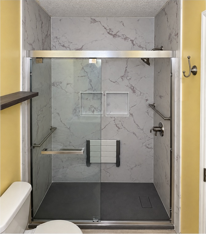 After: marble-look walk-in shower with seating and grab bars in the yellow bathroom