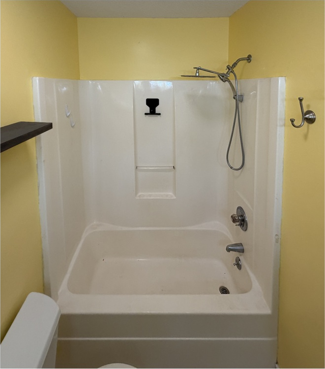 Before: original tub and shower in a yellow bathroom